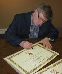 Le président de la Société québécoise d’ethnologie, Jean-Pierre Pichette, signant les certificats de reconnaissances aux artisans acériculteurs. Photo ©chouynard.ca